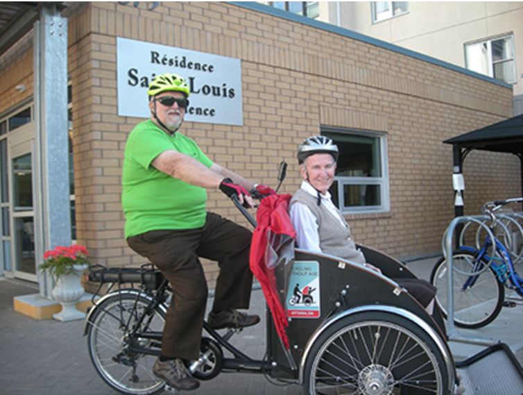 a man riding an adapted bicycle with elder woman